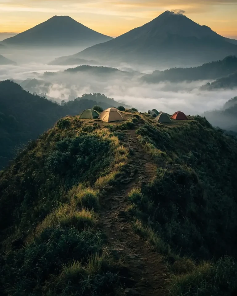 Punggung puncak Gunung Andong dengan deretan tenda dan Gunung Merbabu di belakangnya